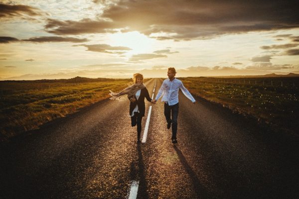 couple running down a road at sunset SEO tips for wedding photographers