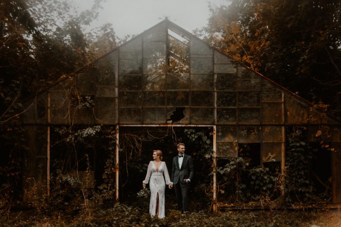 couple in front of overgrown greenhouse