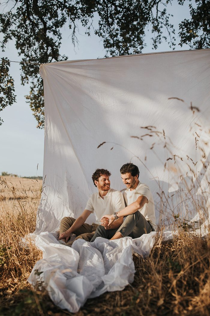 same sex couple posed on sheet in a field