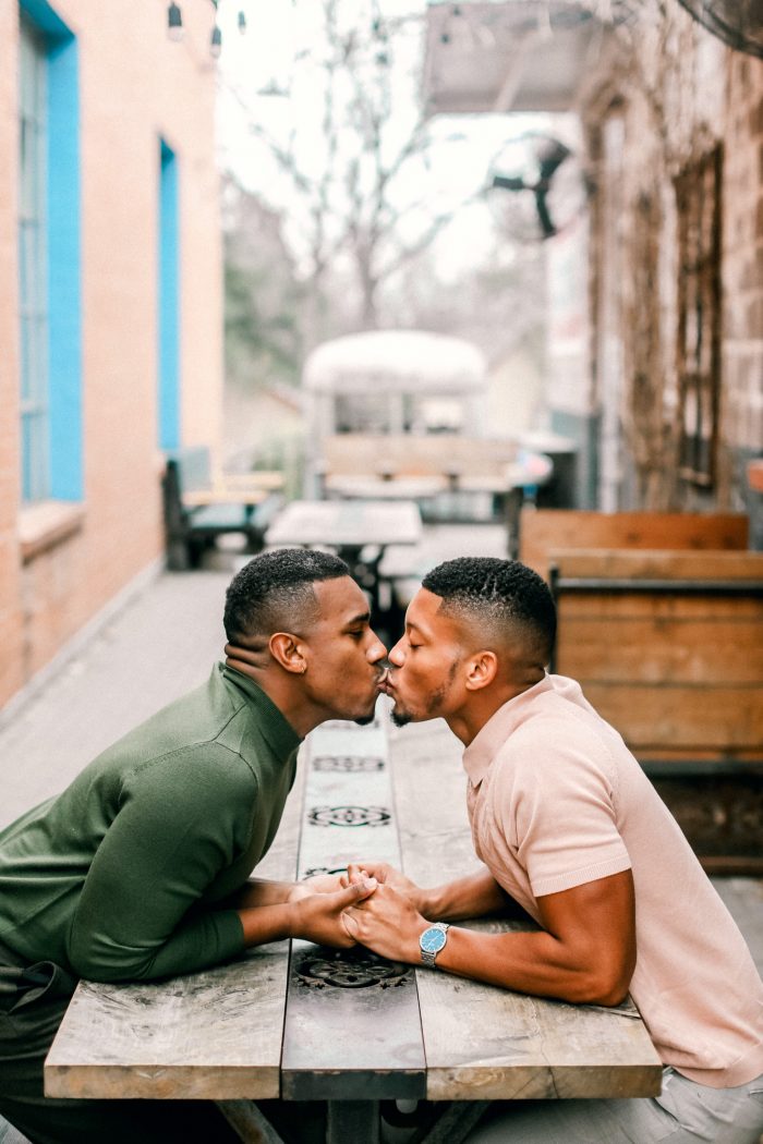 same sex couple kissing over picnic table