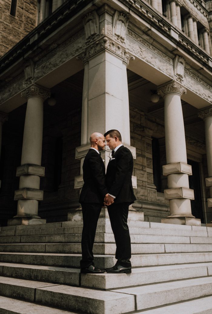 same-sex couple in tuxedos in city