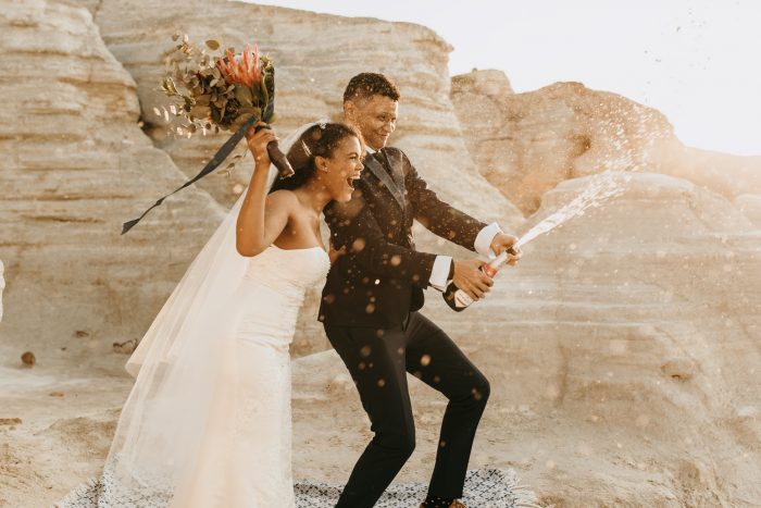 couple popping champagne on wedding day