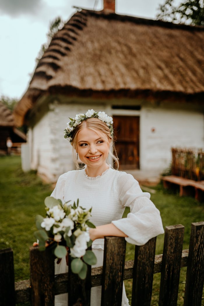 bride posing on fence post of cottage