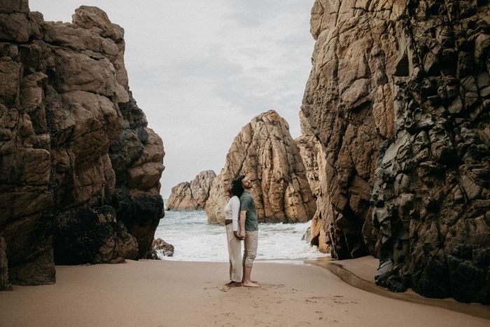 couple on Portugal beach among rocks