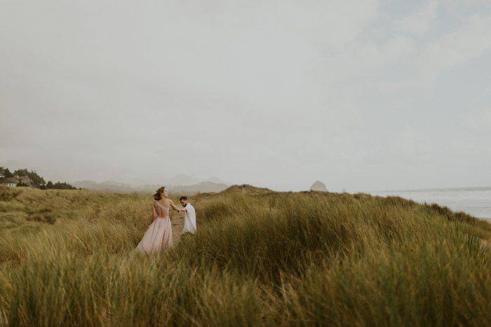 couple walking through tall grass by the sea