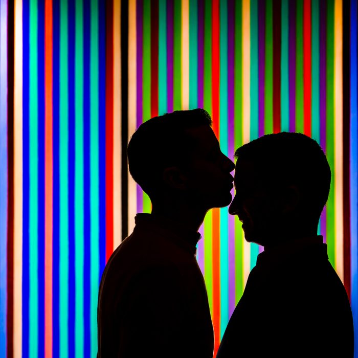 same-sex couple silhouettes in front of colorful wall