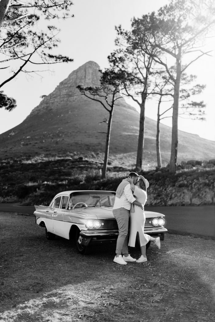 couple kissing in front of vintage car and mountain