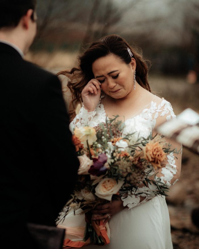 bride wiping tear during vows with partner
