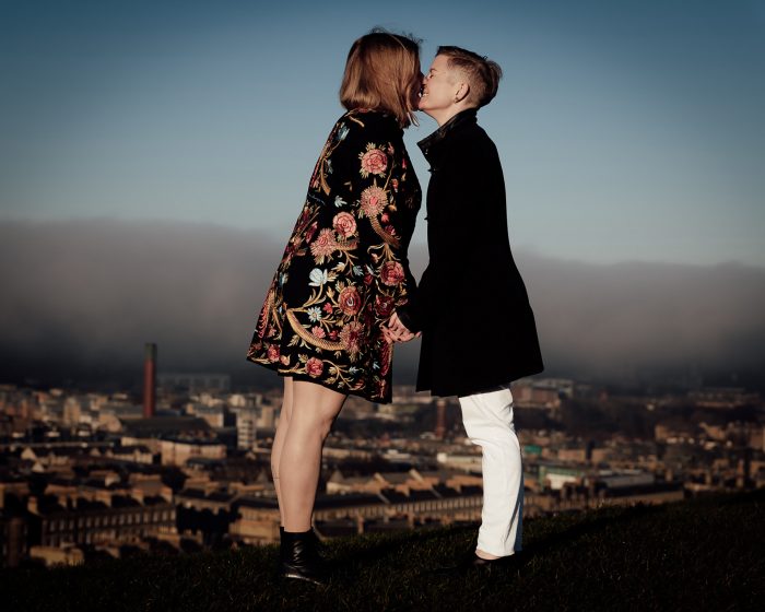 same-sex couple kissing on overlook of Edinburgh