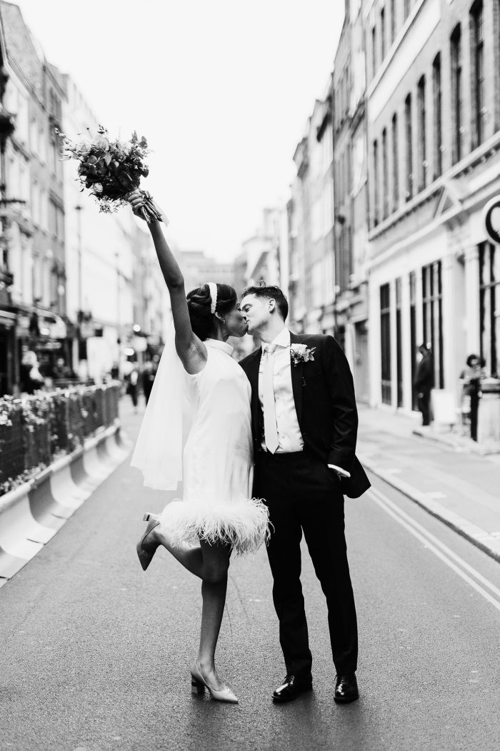 bride in short dress kissing groom in middle of city street