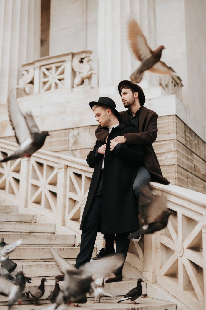 same-sex couple on city stairs with pigeons
