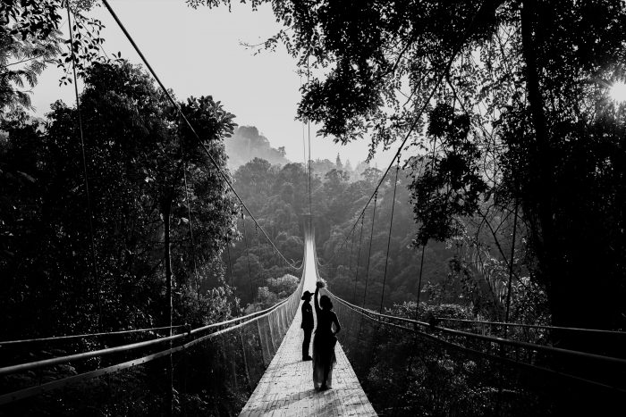black and white photo couple on long suspension bridge