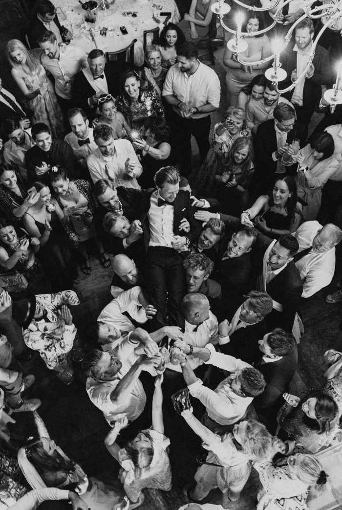 black and white shot of groom crowd surfing