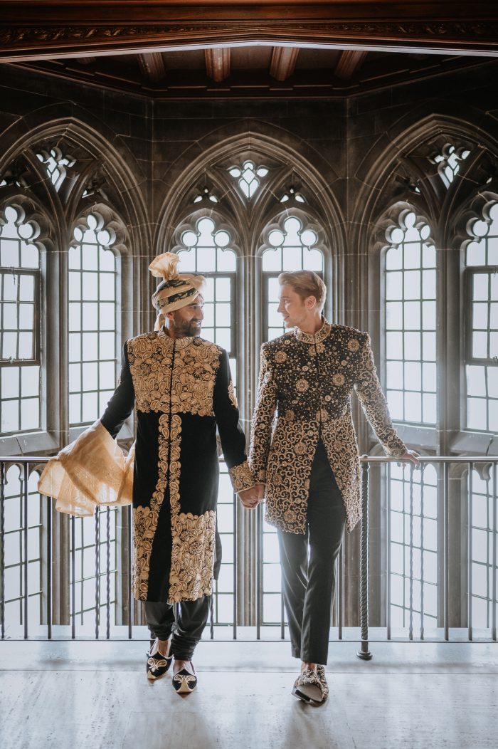 same sex couple with intricate venue windows and garb