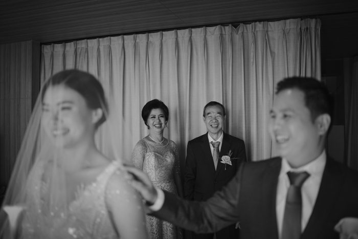parents smiling behind the bride and groom at wedding