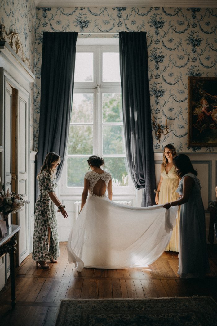 bride getting ready in front of window with bridesmaids