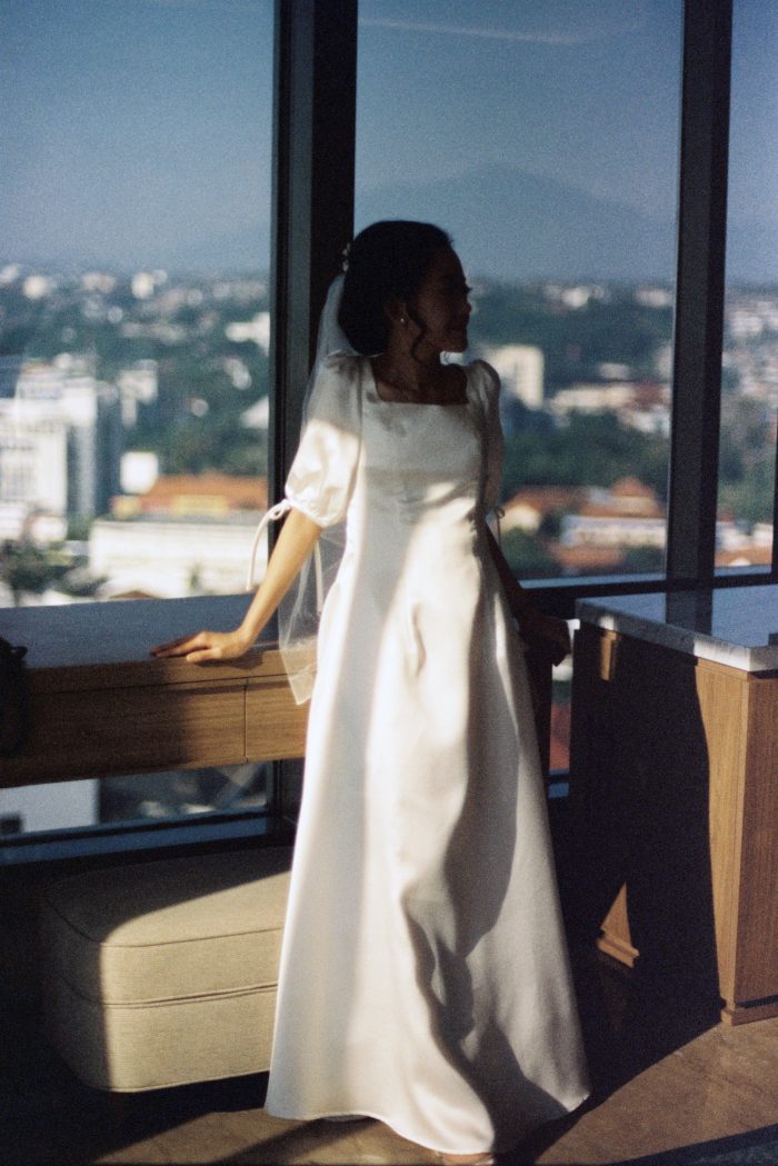 bride reclining in front of city window