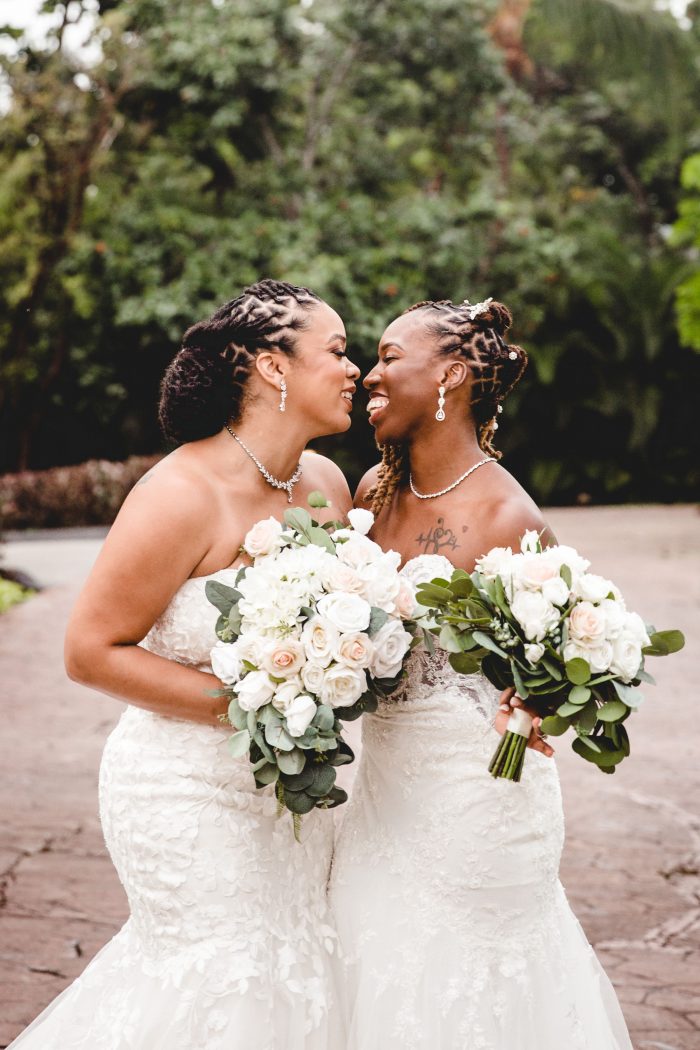 two brides joyfully smiling at each other 