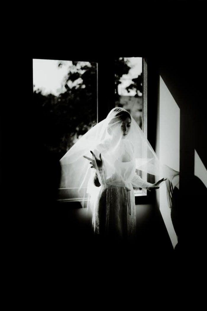 black and white film photo of bride in window