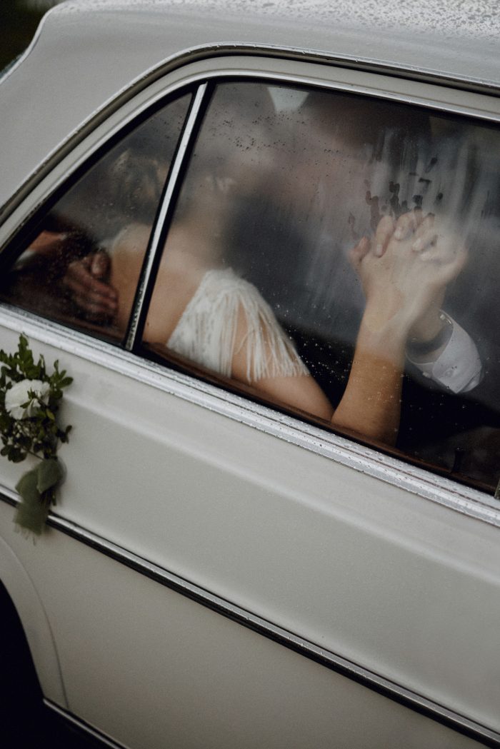 wedding couple inside car kissing against foggy window