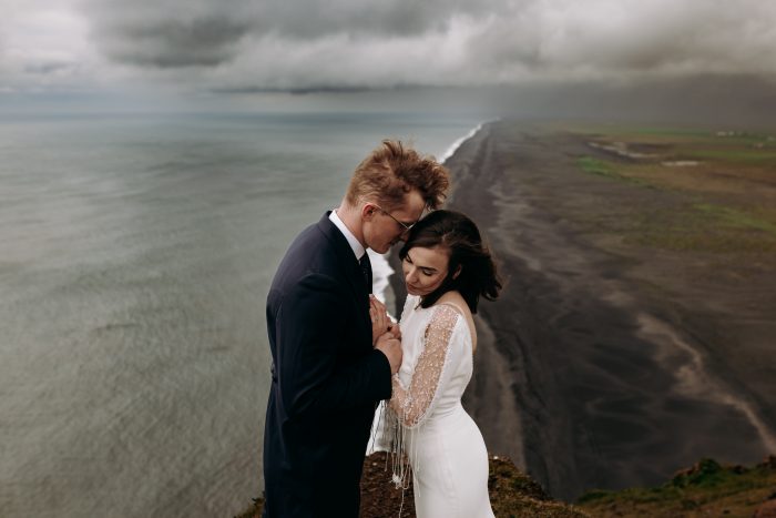 wedding day couple on cliff over Iceland beach