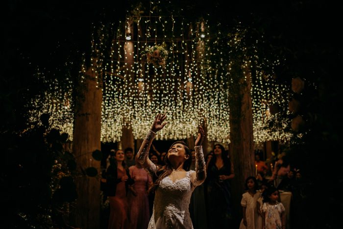 bride tossing bouquet among twinkly lights