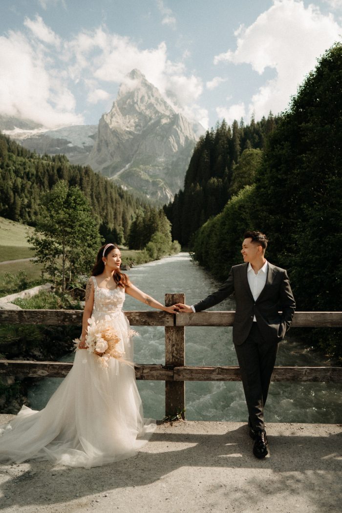 bride and groom on bridge with mountains in the background