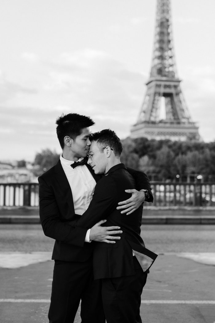 gay couple hugging in tuxes with Eiffel Tower in background