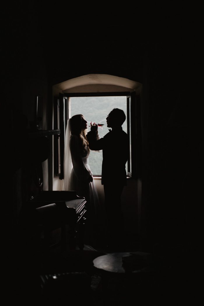 couple toasting wine in a dark room by window