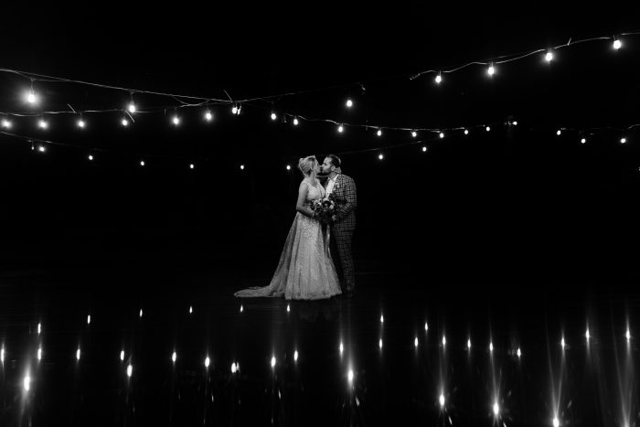 black and white photo of couple under twinkly lights