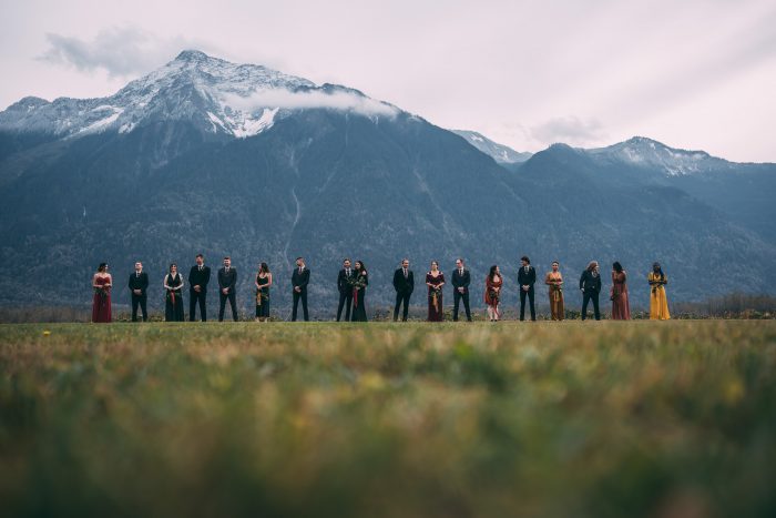 large wedding party posing in front of mountains