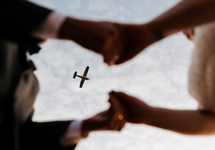 plane flying overhear wedding couple holding hands