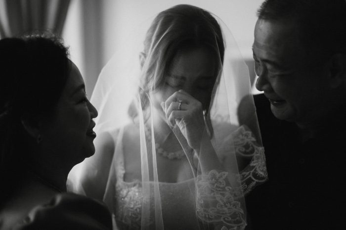 bride crying in between her mother and father