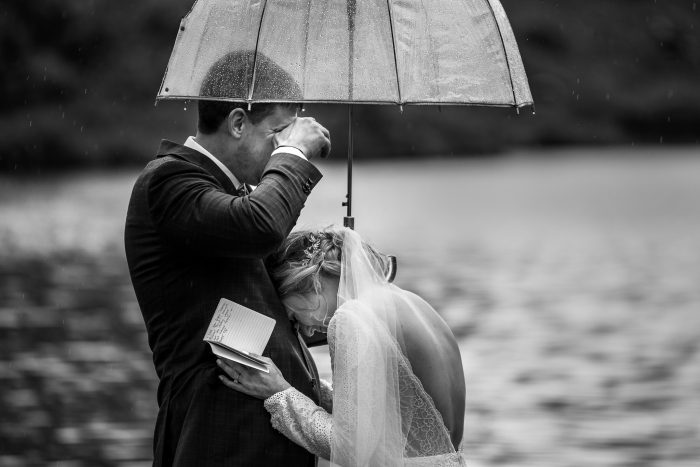 couple crying during vows under umbrella
