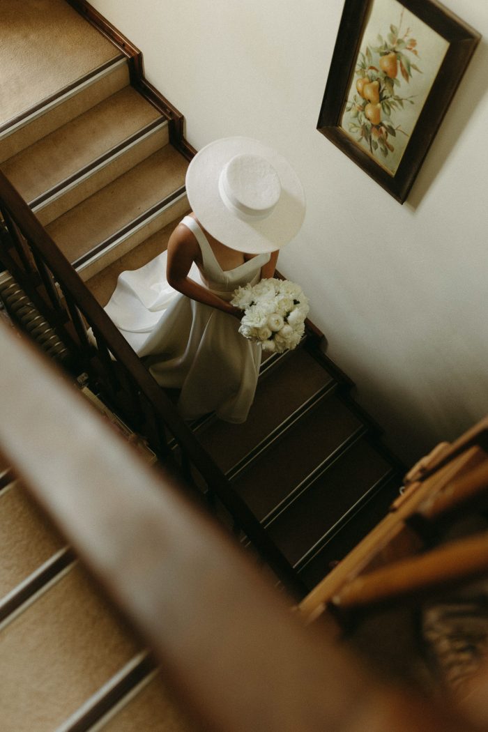 bride in hat walking down stairs