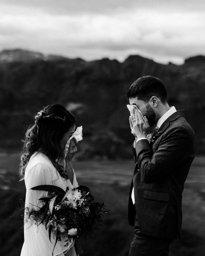bride and groom wiping away tears during vows