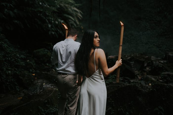 couple walking through jungle with bamboo torches
