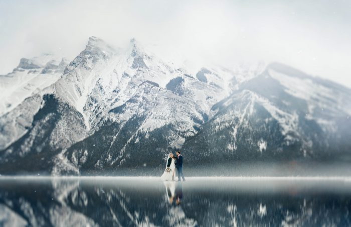 wedding couple on ice in front of snowy mountain range