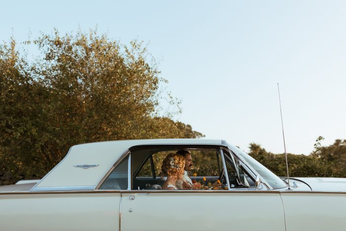 bride and groom sitting in classic car