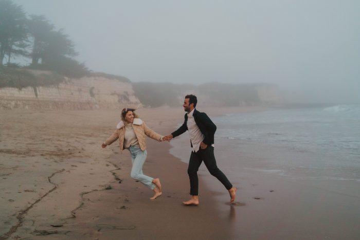 couple running hand in hand on beach