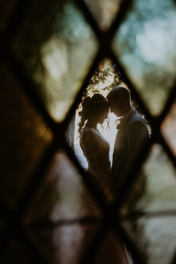wedding day couple posing through stained glass