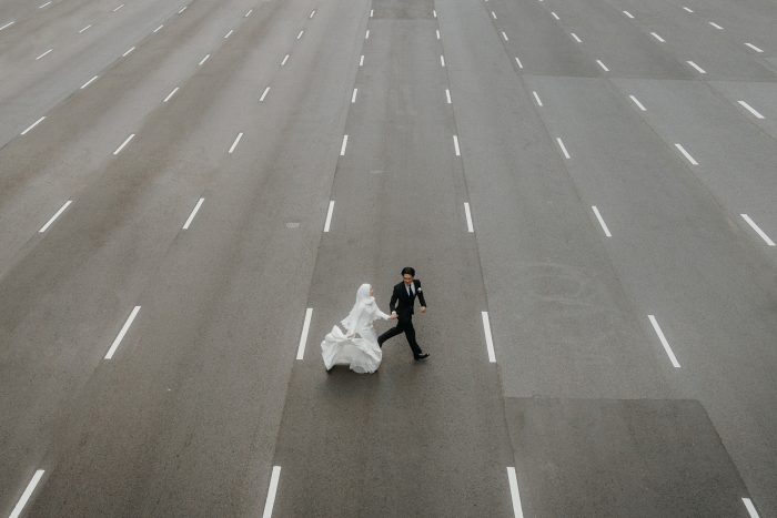 wedding day couple running across empty highway