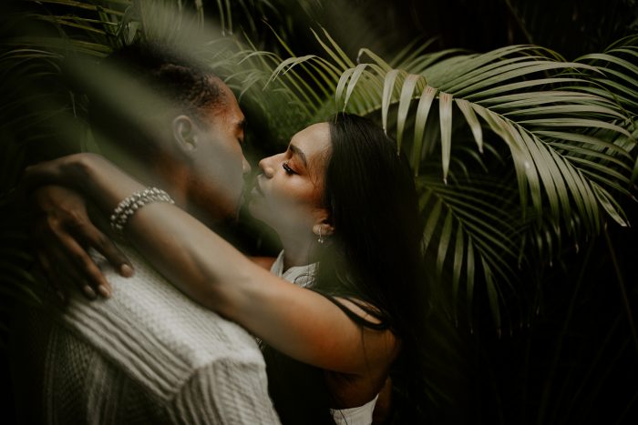 couple embracing amongst tropical leaves