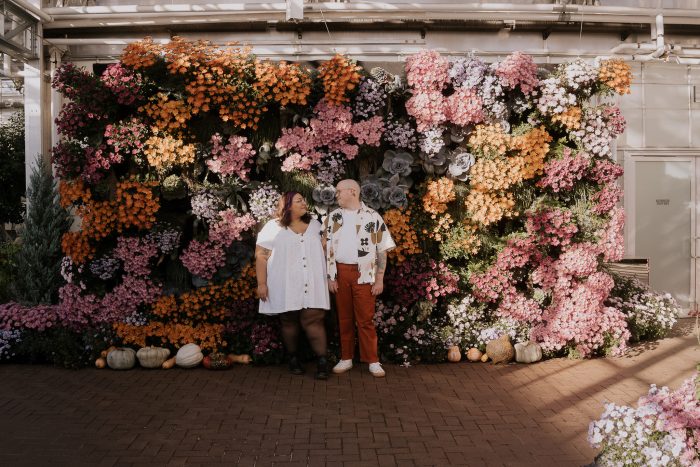 photo de fiançailles devant un mur fleuri