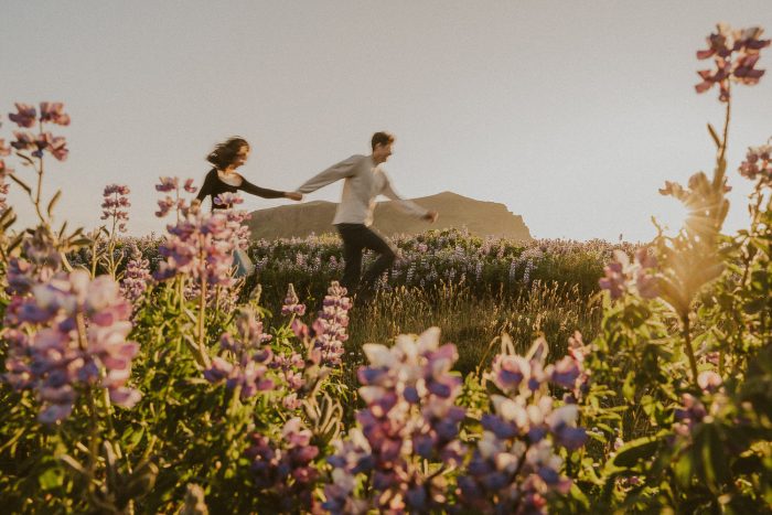 couple running hand in hand through wildflowers