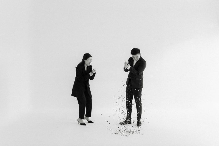 black and white photo couple popping confetti in studio