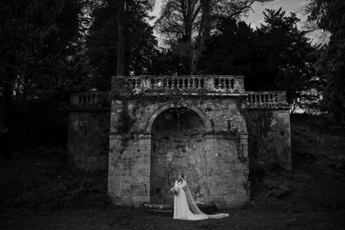 bride alone in black and white wide shot in mystical garden