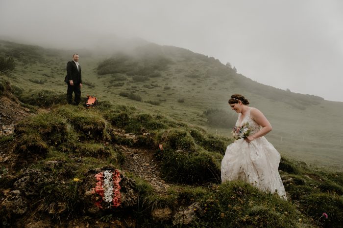 wedding couple hiking up hill in fog