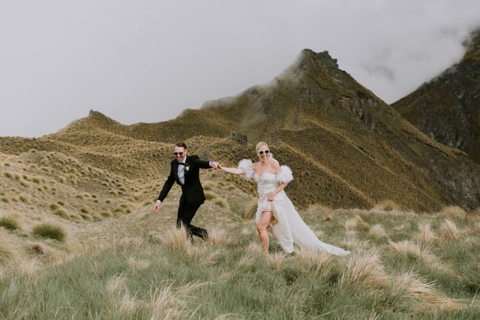 fashionable wedding day couple running through hills