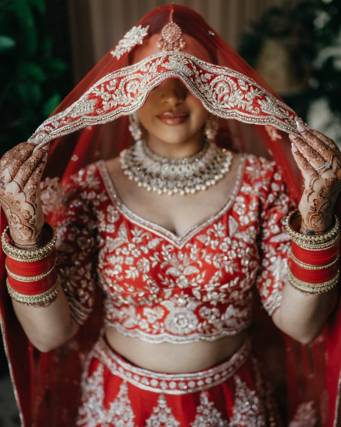 South Asian bride in red dress and veil